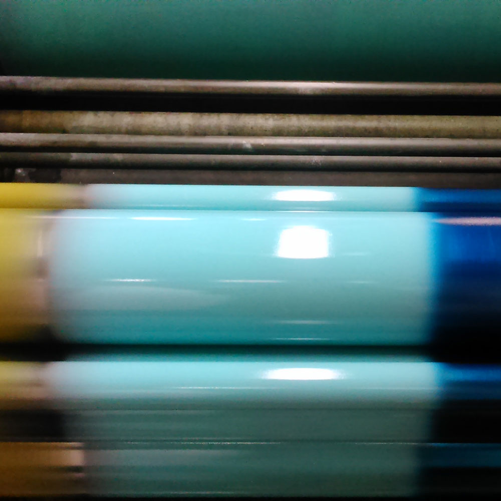 The printing roller is spinning when the ink is applied. Karen uses three colors at the same time, creating a gradient.